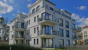 A multi-story residential building with balconies, large windows, and a well-maintained lawn.