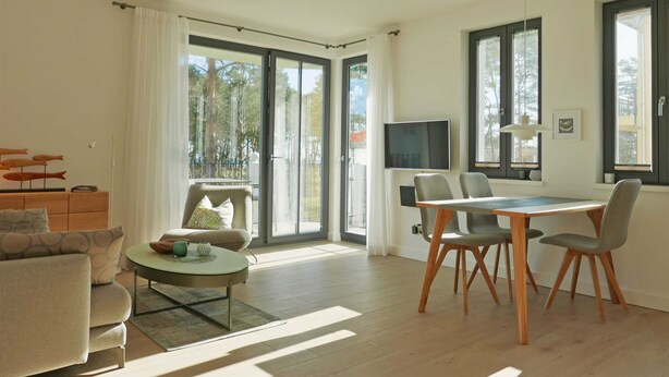 A modern living room with a sofa, coffee table, and dining area with chairs and a TV.