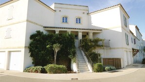 Un immeuble de deux étages avec une façade blanche, une entrée centrale avec des marches et un petit balcon au deuxième étage.