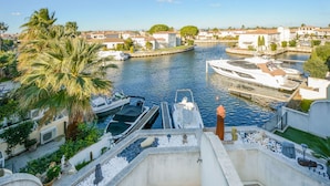 Un canal bordé de bateaux à quai, entouré d’immeubles résidentiels et de palmiers.
