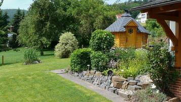 A wooden cabin with a stone retaining wall and a well-maintained lawn.
