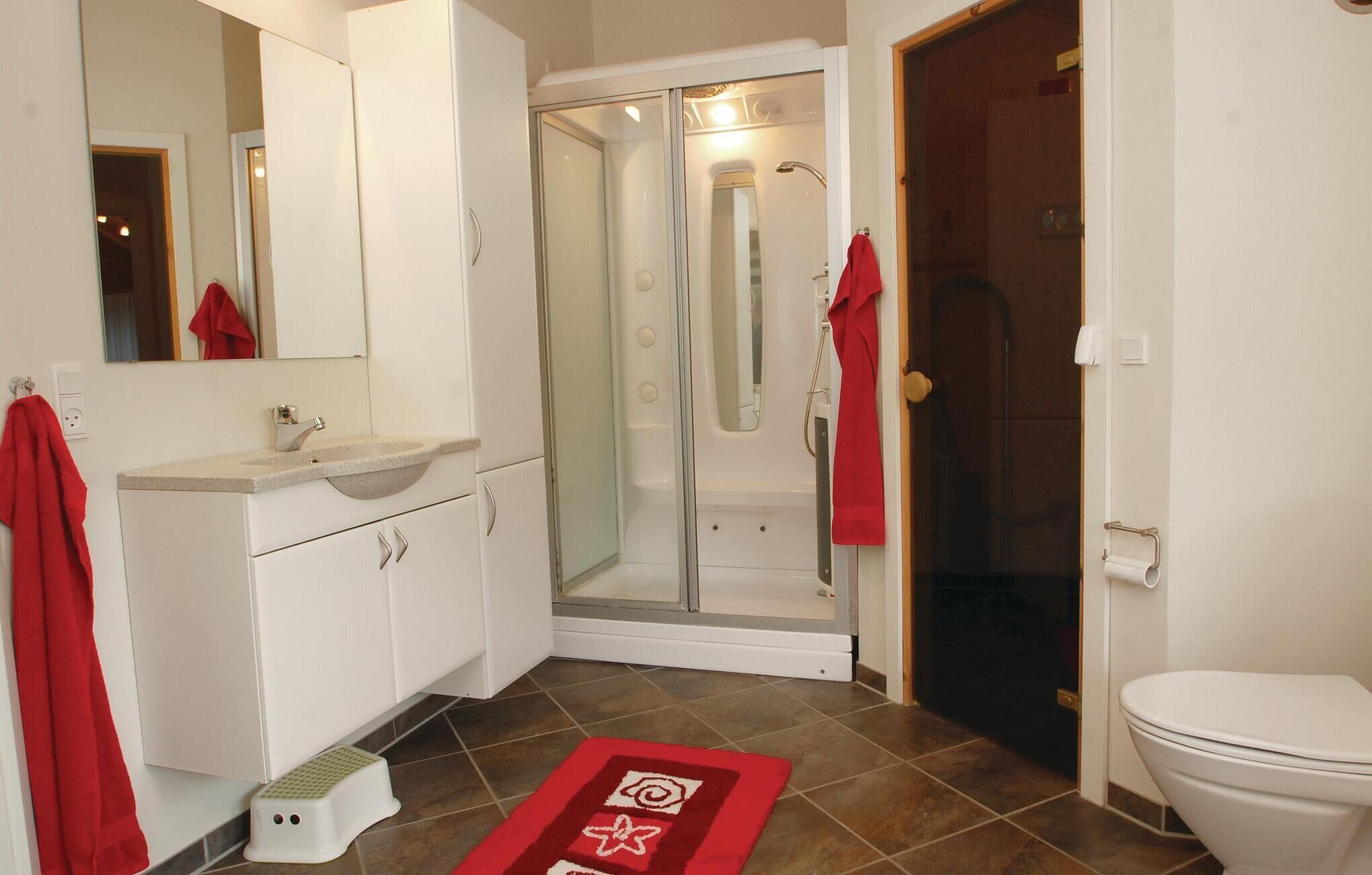 Een badkamer met een wastafel, spiegel, toilet en douche.