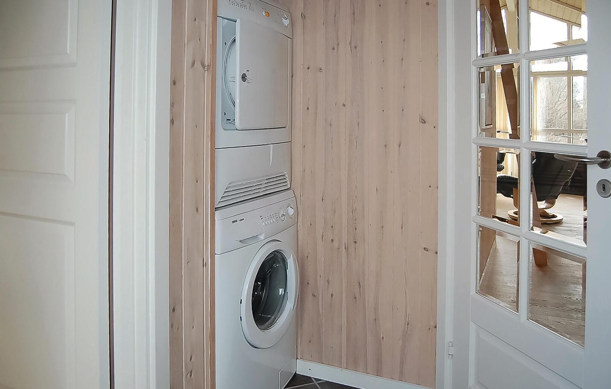 A compact laundry room with a washing machine, dryer, and stacked dryers.