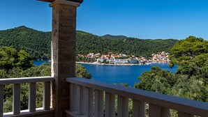 Une ville côtière dotée d’une jetée en pierre, de collines verdoyantes et d’une mer d’un bleu limpide.