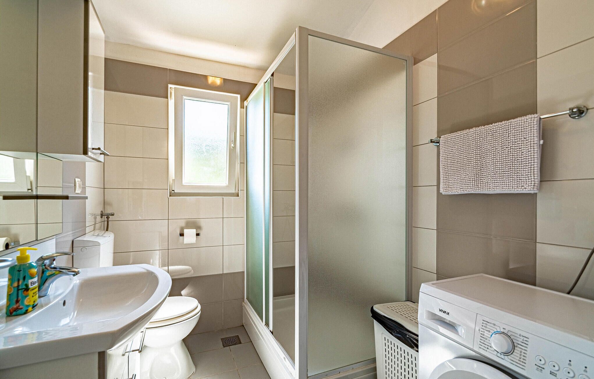 Ein modernes Badezimmer mit Toilette, Waschbecken und einer Waschmaschine.