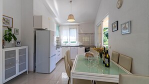 Une cuisine de taille réduite comprenant un réfrigérateur, une table à manger avec des chaises et un luminaire suspendu.