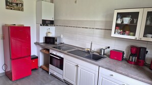 Een keuken met een rode koelkast, een magnetron, een spoelbak en kastjes.