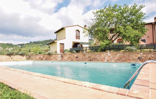 A swimming pool with a stone wall and a wooden deck, surrounded by a stone wall and a tree. - Nice home in Toiano PI with WiFi (Toiano PI)