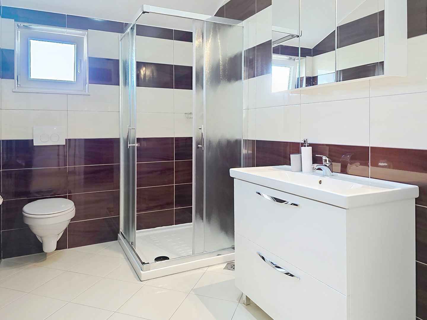 A modern bathroom with a glass shower enclosure, a white sink, and a toilet.