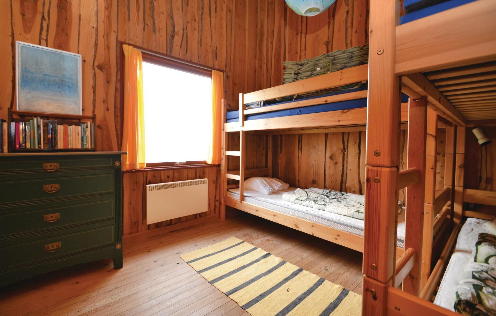 Ein Holzhütten-Zimmer mit Etagenbetten, einem Schminktisch, einem Heizkörper und einem Fenster mit Vorhängen.
