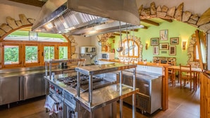 A kitchen with stainless steel appliances, a stone wall, and a green wall with framed pictures.