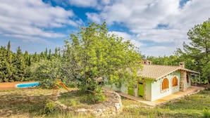 A house with a tiled roof, a swimming pool, and a stone wall.