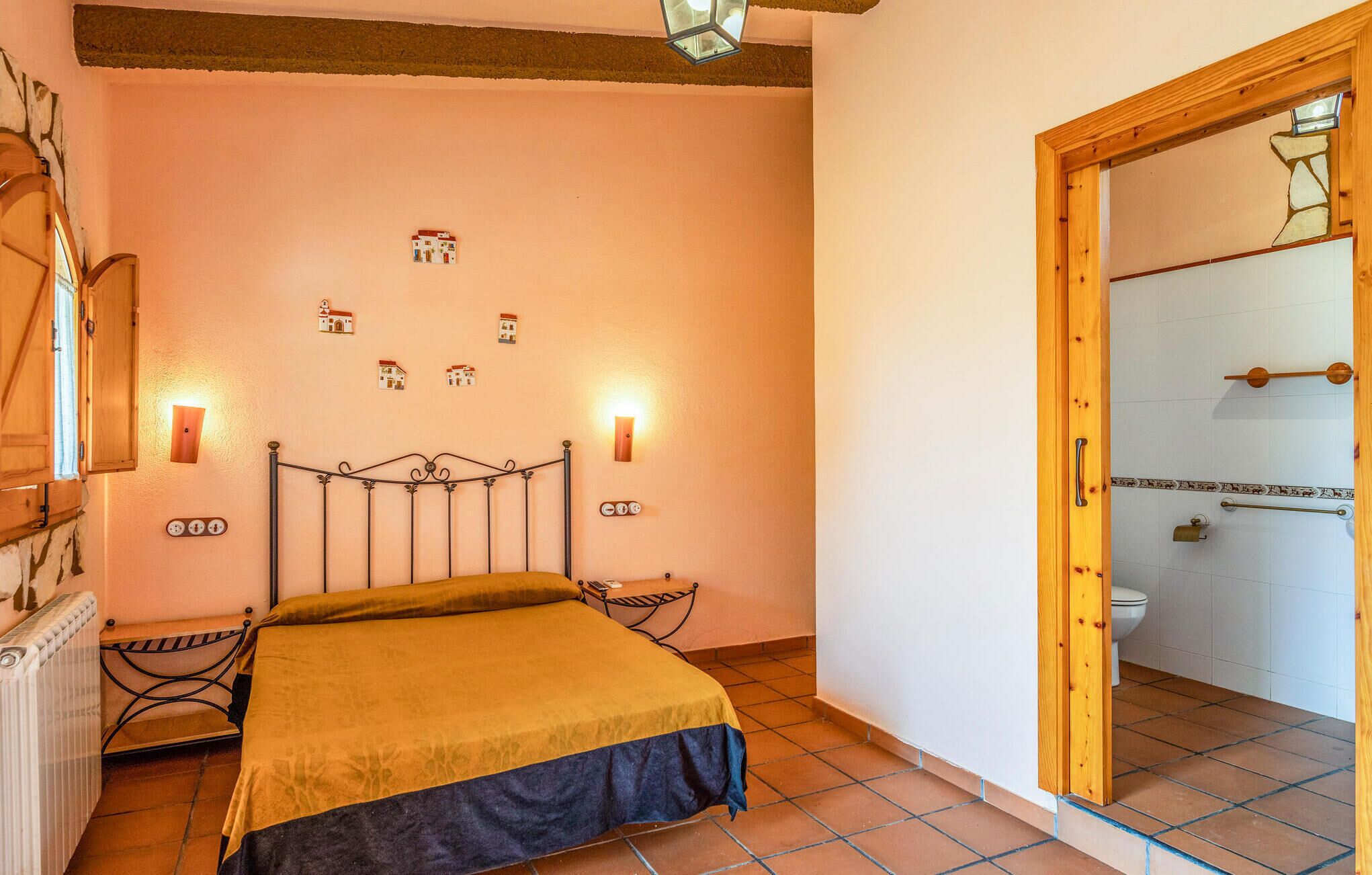 Un dormitorio con cama, un radiador, una puerta de madera y un ventanal pequeño.