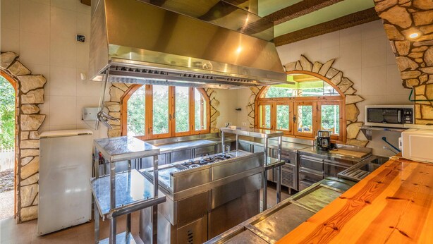 A modern kitchen with stone walls, large windows, and stainless steel appliances.