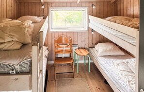Ein kleines Zimmer mit Stockbetten, einem kleinen Schreibtisch und einem Fenster mit Blick auf Grünflächen.