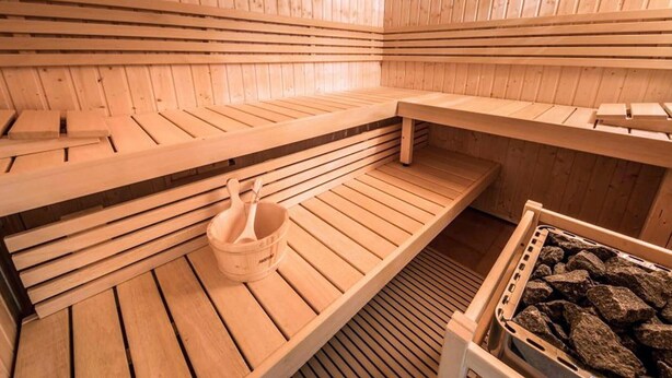 A sauna with wooden benches and a stone basin.