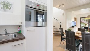 A modern kitchen with a built-in oven, a dining area with a table and chairs, and a view of the outdoors.
