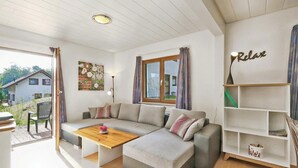 A modern living room with a sectional sofa, a wooden coffee table, and a bookshelf.