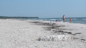 A sandy beach with people, some standing and some sitting, near the water. - 3 bedroom beautiful home in Nexø (Nexø)