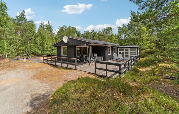 A cabin with a deck, outdoor seating, and a grill.