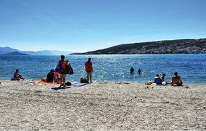 A pebble beach with people sunbathing and swimming in the water. - Amazing home in Zedno (Zedno)
