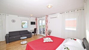 Une pièce comprenant un lit, un canapé, une petite table et une chaise. Il y a une fenêtre donnant sur l’extérieur.