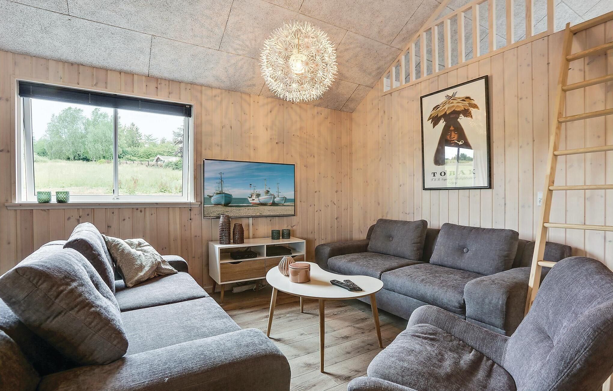 A cozy living room with a wooden interior, a television, a painting, and a ladder.