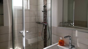 Un bagno moderno con cabina doccia in vetro, lavandino bianco e specchio.
