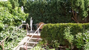 A garden with a stone staircase, a white statue, and a variety of plants.