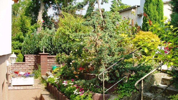 A garden with a brick wall, a small table with flowers, and a staircase.