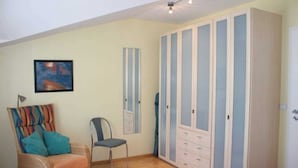 Une chambre à coucher avec un lit, une chaise, une armoire et un tableau au mur.