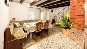 Un comedor con una mesa dispuesta para cuatro personas, un sofá y una escalera.