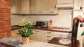Cocina con armarios de madera, microondas, estufa a gas y pared de ladrillo.