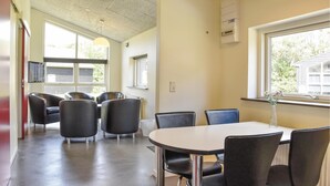Ein Konferenzraum mit rundem Tisch und sechs Stühlen, großen Fenstern und einer Decke mit eingelassener Beleuchtung.