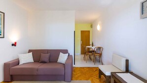Un salon comprenant un canapé, une petite table et un coin repas avec des chaises.