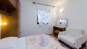 Une chambre à coucher comprenant un lit, une table de chevet, une chaise, un miroir et une armoire.