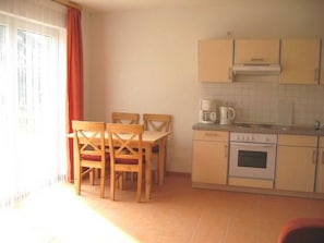 Una cocina compacta con una mesa de comedor y sillas, una cafetera y una estufa.
