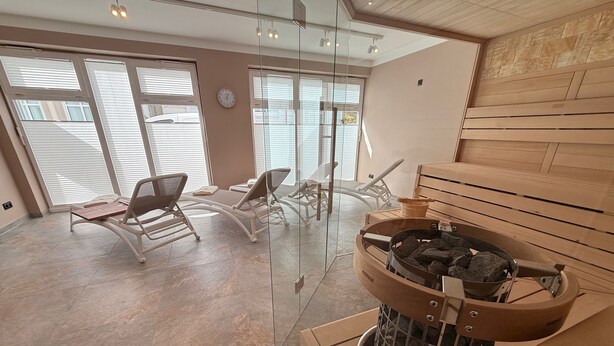Une salle de spa moderne équipée d’un sauna, de fauteuils inclinables et d’une cheminée fermée par une vitre.