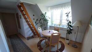 Ruokailutila, jossa on pyöreä pöytä, tuoleja, lamppu ja ruukkukasveja.