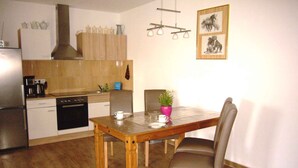 Een moderne keuken met houten kastjes, een eettafel met stoelen en een hanglamp.