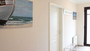Een gang met een witte deur, een witte radiator en een lijst met een foto van een boot aan de muur.