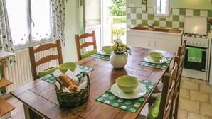 Ein Essbereich mit Holztisch, gedeckt für zwei Personen, einem Brotkorb und einer Blumenvase.