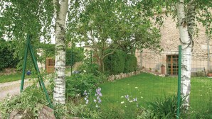 Ein Garten mit einem Steinhaus, einem Holzzaun und verschiedenen Pflanzen.