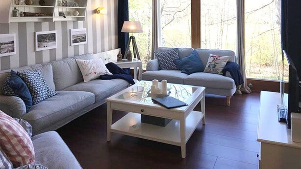 Ein Wohnzimmer mit gestreifter Tapete, einem Sofa, einem Couchtisch und einer Lampe.