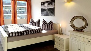 Ein Schlafzimmer mit Bett, Nachttisch, Kommode und einem an der Wand hängenden Bild.