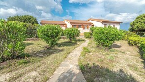 A residential property with a stone pathway leading to a house with a tiled roof.