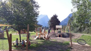 Un parque infantil con columpios, estructuras para escalar y un arenero.