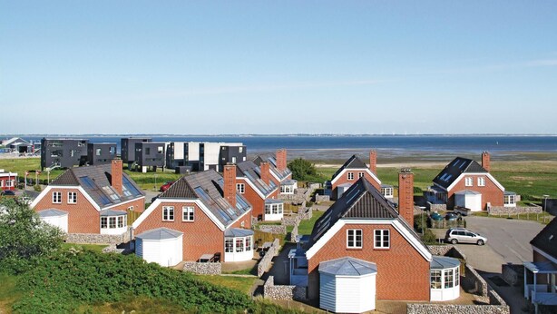 Uma área residencial costeira com casas de telhados inclinados e construção em tijolo, algumas com garagens anexas.