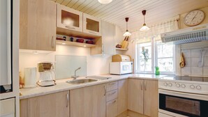Una cocina con armarios de madera, un fregadero, una estufa y una ventana con vistas a árboles.