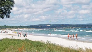 Una playa con gente nadando y caminando por la orilla.
